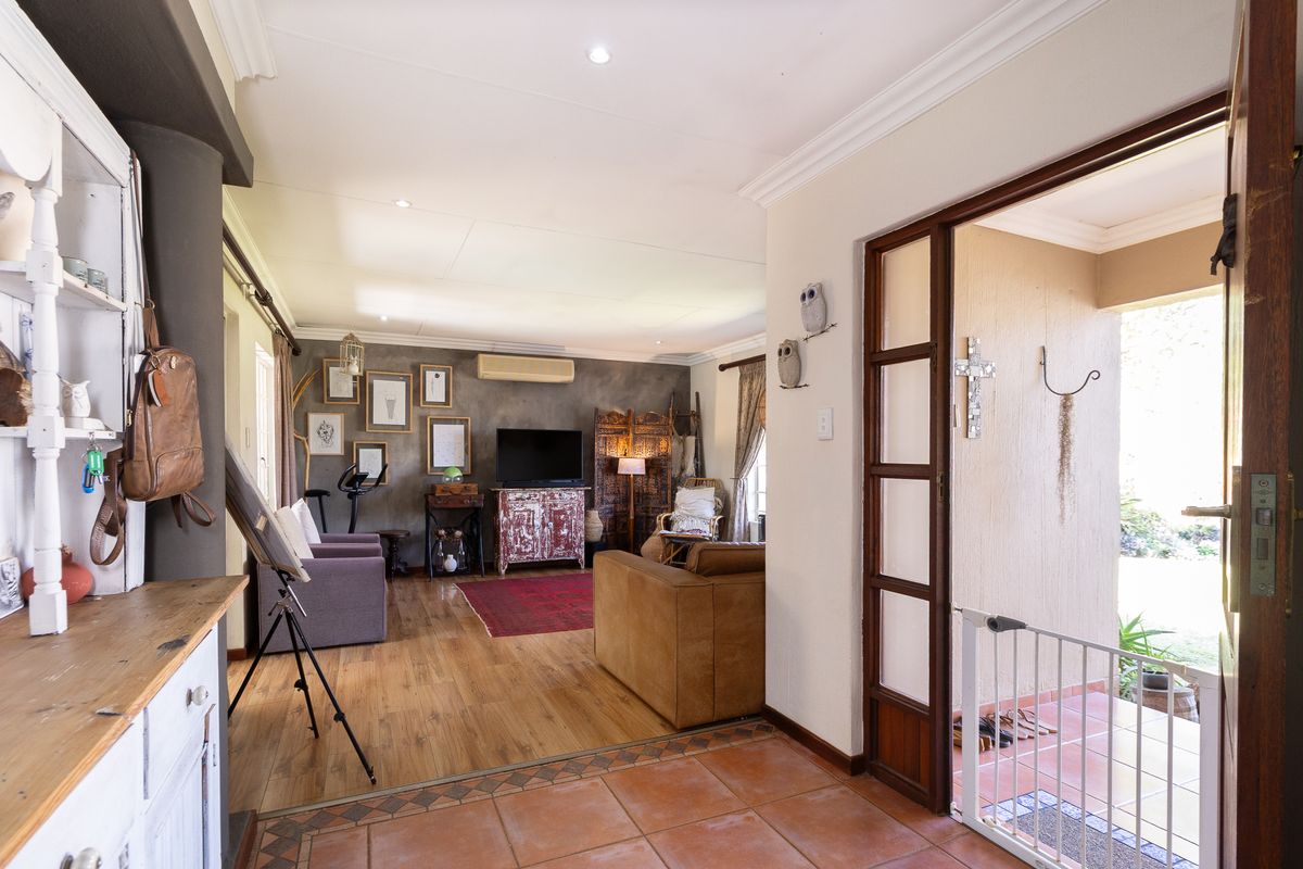 Open-plan living area featuring laminate flooring, recessed lighting, and an air conditioning unit, with direct access to an outdoor patio through a timber-framed door.