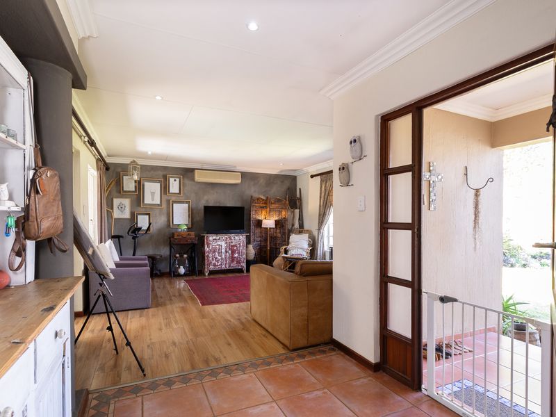 Open-plan living area featuring laminate flooring, recessed lighting, and an air conditioning unit, with direct access to an outdoor patio through a timber-framed door.