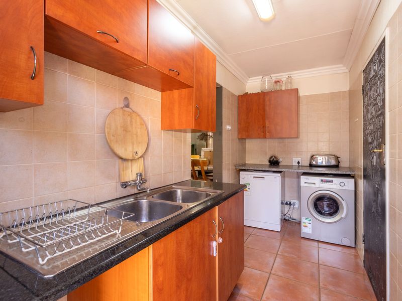 Functional scullery featuring double bowl sink, granite countertops, ample laminate cabinetry, and dedicated spaces for laundry and dishwashing appliances.