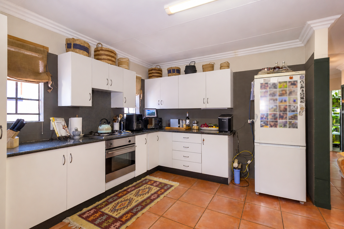 Functional kitchen featuring white cabinetry, granite countertops, stainless steel oven, gas hob, and tiled flooring with neutral wall finishes.