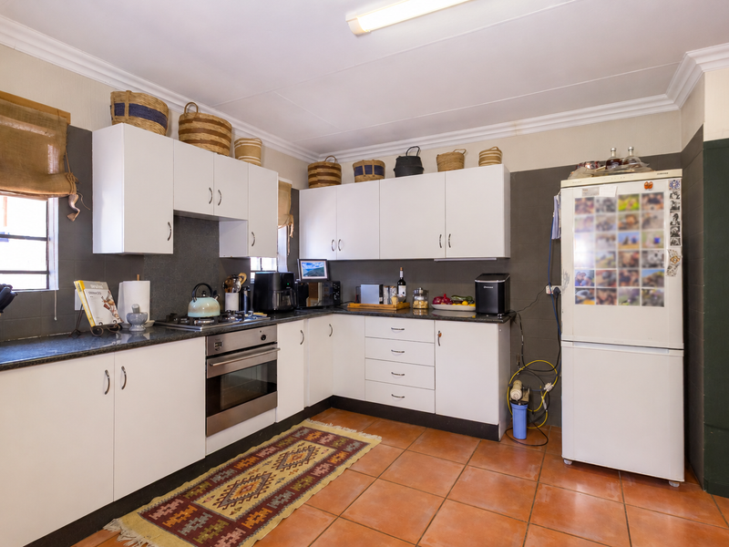 Functional kitchen featuring white cabinetry, granite countertops, stainless steel oven, gas hob, and tiled flooring with neutral wall finishes.