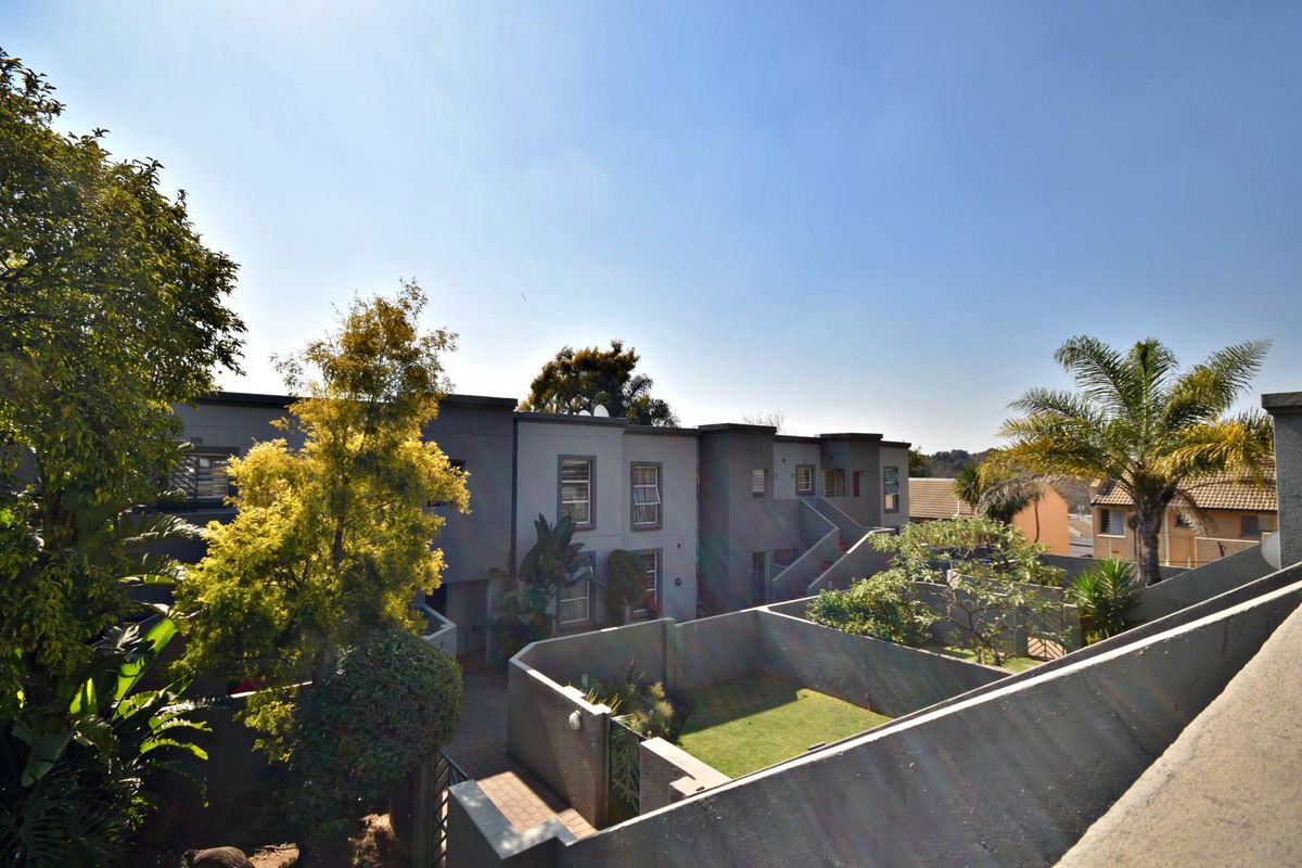 An elevated view of the apartment complex rear exterior, featuring private garden spaces, paved walkways, and modern building architecture.