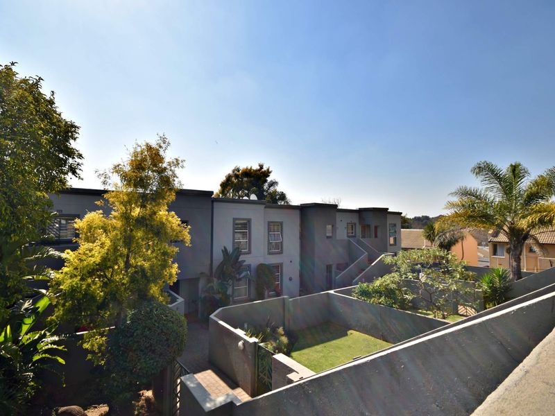 An elevated view of the apartment complex rear exterior, featuring private garden spaces, paved walkways, and modern building architecture.