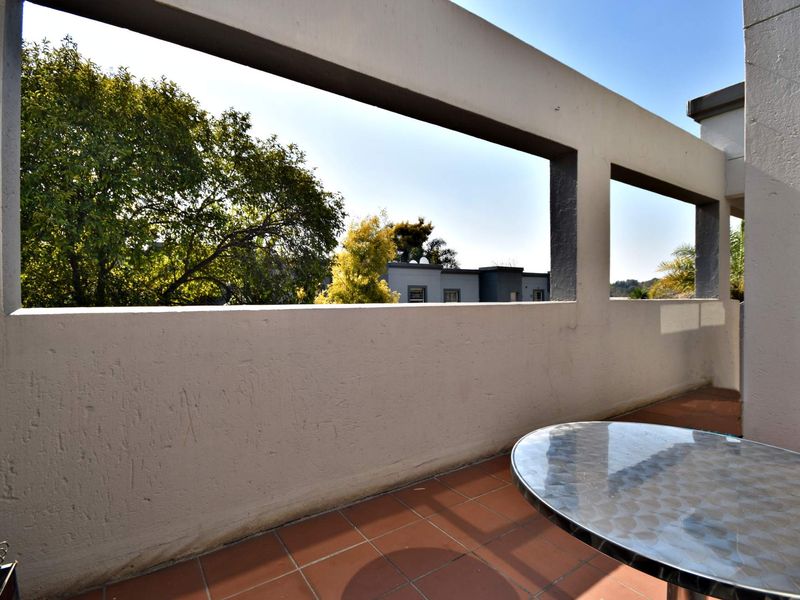 A spacious open-air balcony featuring tiled flooring and a concrete balustrade, offering an elevated outdoor space with neighborhood views.