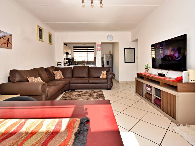Open plan living area featuring tiled flooring and a seamless transition into the kitchen space, providing a functional and connected layout.