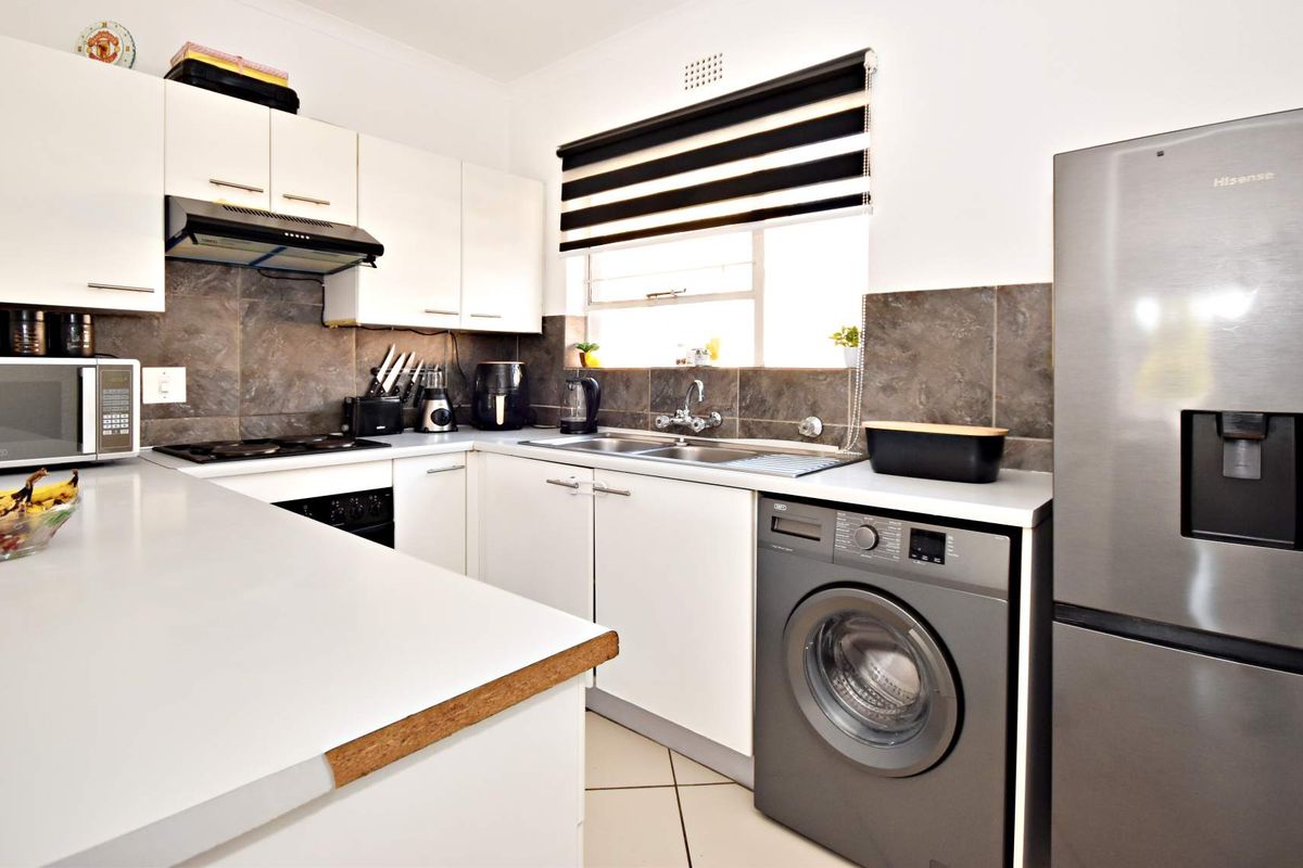 A functional kitchen featuring white cabinetry, dark tiled backsplash, built-in oven and hob, and integrated space for a washing machine.