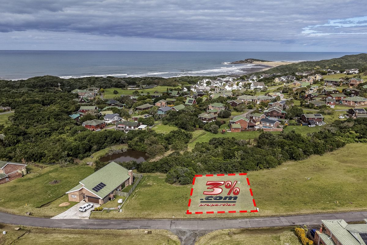 An aerial view of a vacant residential plot situated in a coastal estate, offering proximity to the ocean and surrounding natural landscape.