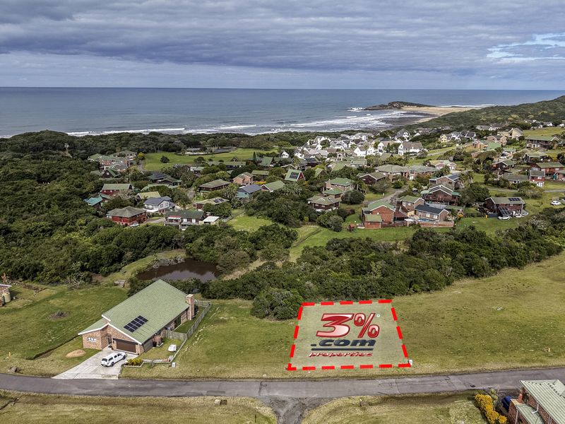 An aerial view of a vacant residential plot situated in a coastal estate, offering proximity to the ocean and surrounding natural landscape.