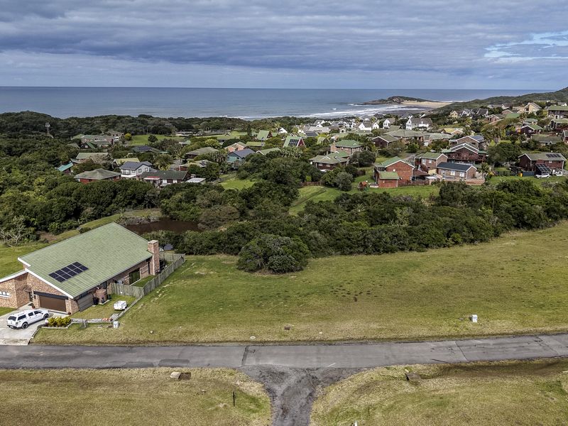 Aerial view of a vacant residential plot situated in a coastal estate, offering scenic views of the surrounding landscape and nearby ocean.