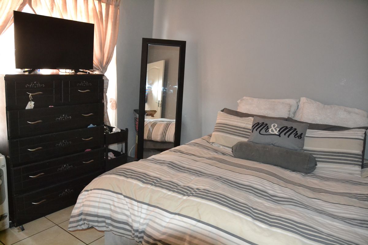 A functional bedroom featuring tiled flooring and neutral wall finishes, providing a comfortable and practical living space.