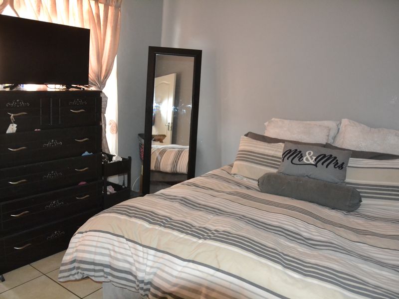 A functional bedroom featuring tiled flooring and neutral wall finishes, providing a comfortable and practical living space.