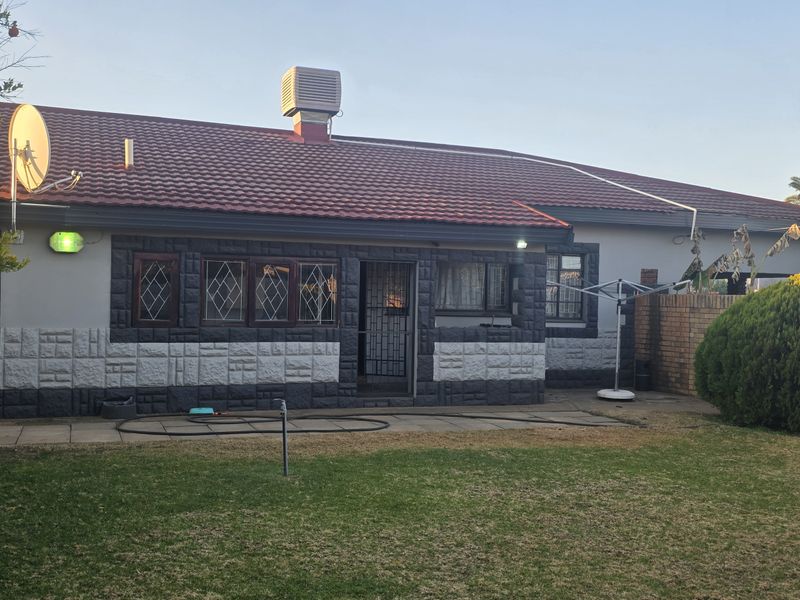 Rear view of the property featuring a tiled roof, paved patio area, and a private garden enclosed by a brick boundary wall.
