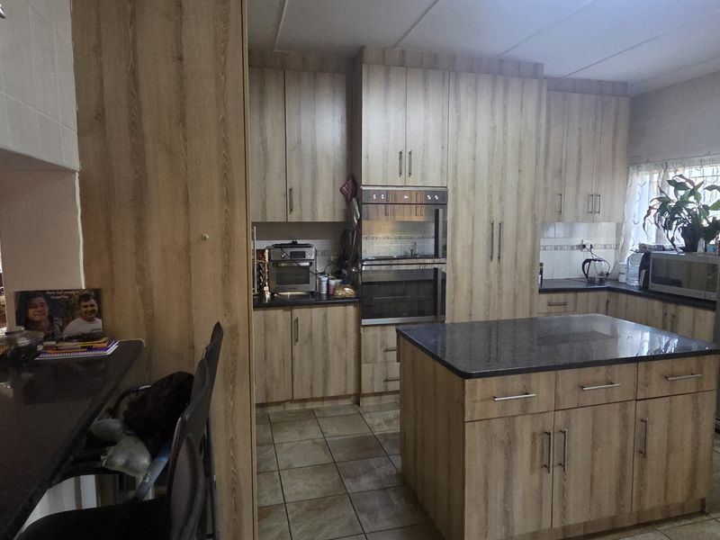 A functional kitchen featuring wood-look cabinetry, a central island with stone countertops, and a built-in double oven, providing ample storage and workspace.