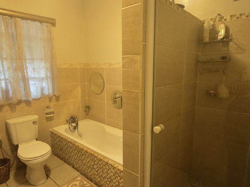 A functional bathroom featuring a pedestal basin, toilet, built-in bathtub, and a separate glass-enclosed shower with tiled finishes.