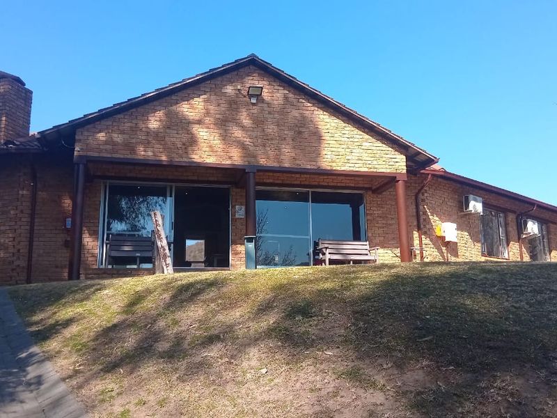 Front elevation of a brick-built small holding property featuring a tiled roof, sliding glass doors, and a paved driveway approach.