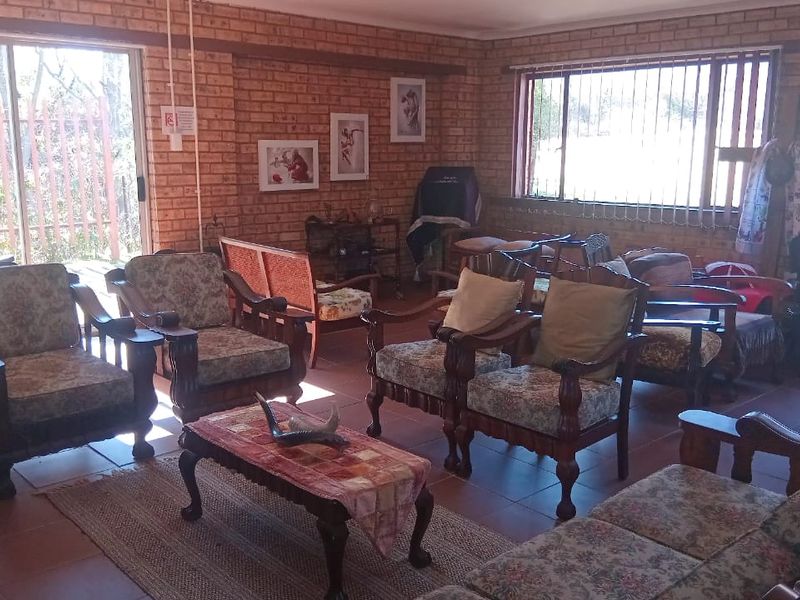 Spacious living room featuring exposed brick walls, tiled flooring, and large windows that provide ample natural light and access to the exterior.