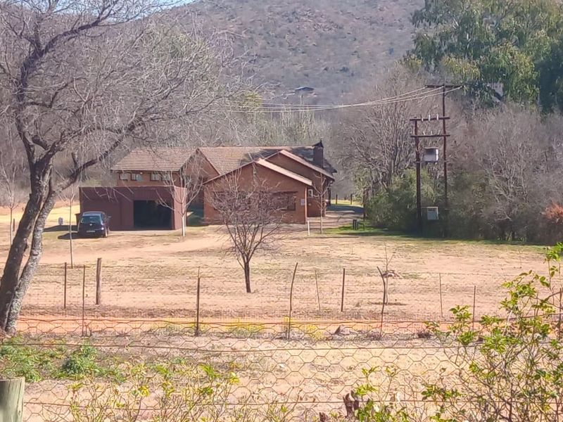 A wide-angle view of a brick-faced small holding property featuring a tiled roof, attached garage, and surrounding rural landscape.