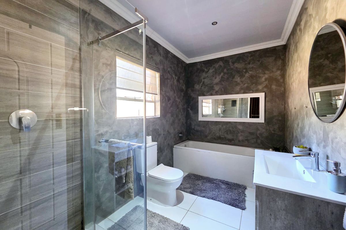 Modern bathroom featuring a glass-enclosed shower, built-in bathtub, vanity cabinet, and contemporary textured wall finishes.