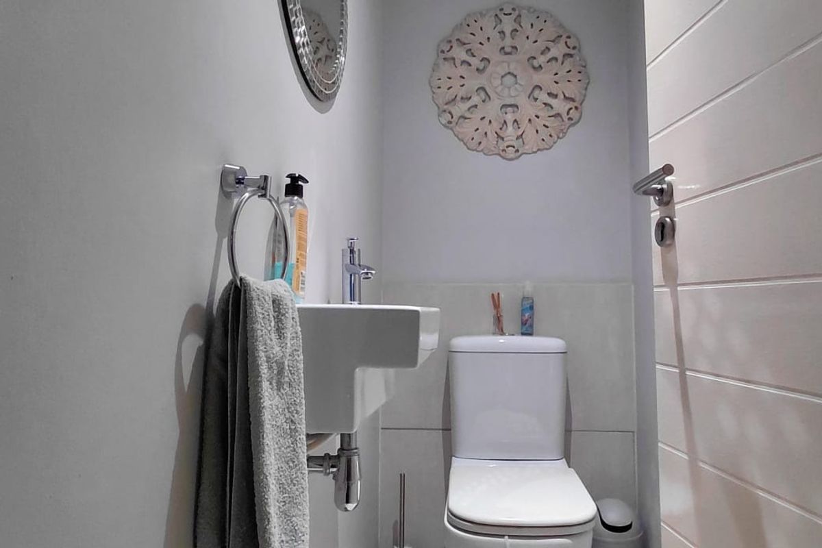 A compact guest bathroom featuring a wall-mounted basin, modern toilet, and clean white finishes.