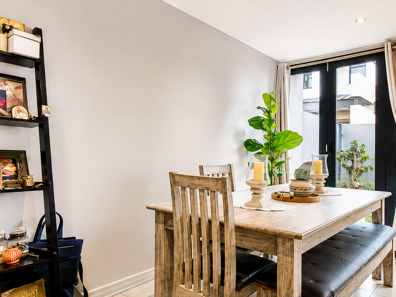 Bright dining area featuring modern bi-fold doors that open to a private outdoor space, complemented by neutral walls and tiled flooring.