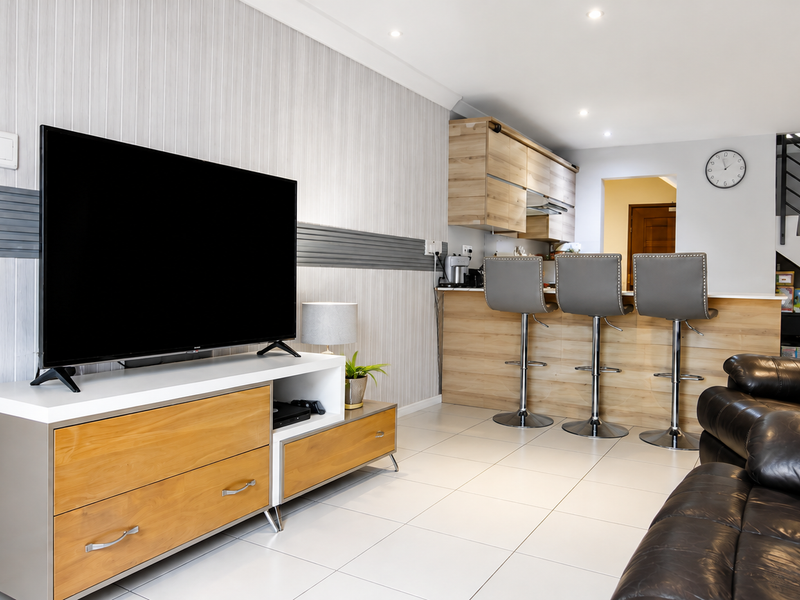 Open-plan living area featuring a modern kitchen with breakfast bar, tiled flooring, and a staircase leading to the upper level.