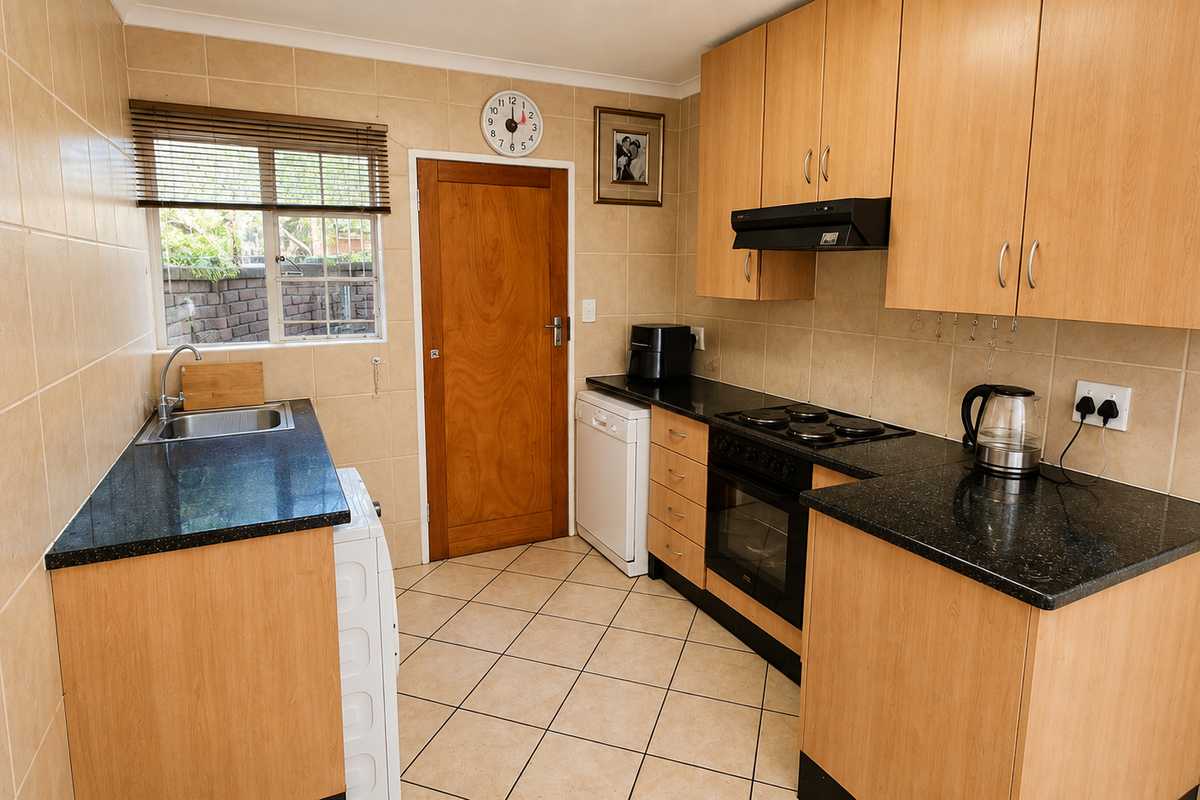 A functional kitchen featuring laminate cabinetry, granite countertops, built-in oven with hob, and tiled finishes throughout.