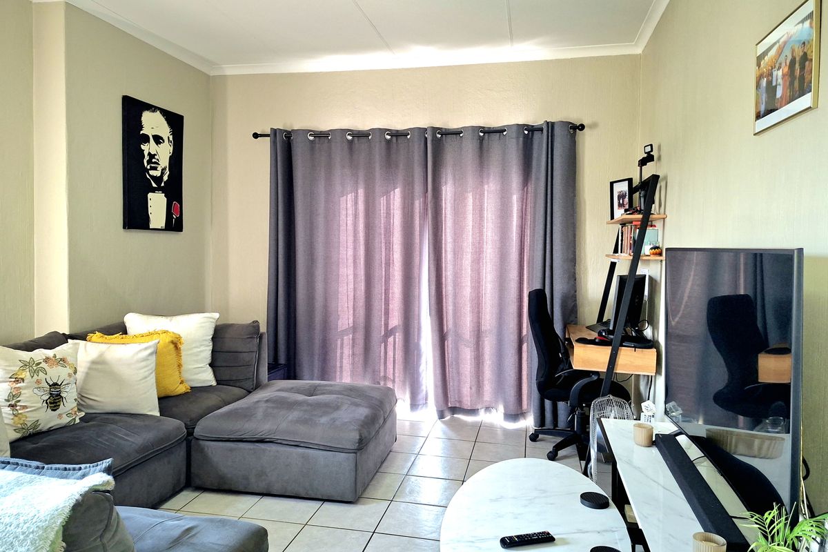 A comfortable living room featuring tiled flooring and a sliding door with curtains, providing access to the outdoor area.