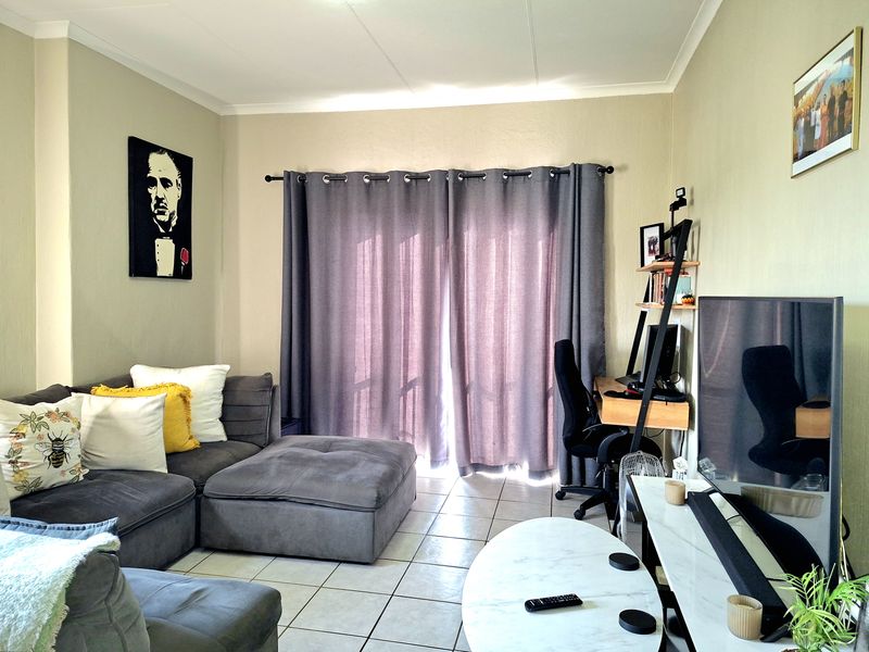 A comfortable living room featuring tiled flooring and a sliding door with curtains, providing access to the outdoor area.