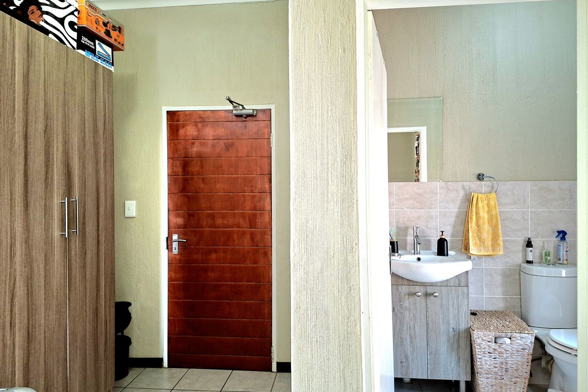 A functional bathroom featuring a vanity cabinet with a basin, wall-mounted mirror, and toilet, finished with tiled splashbacks and flooring.