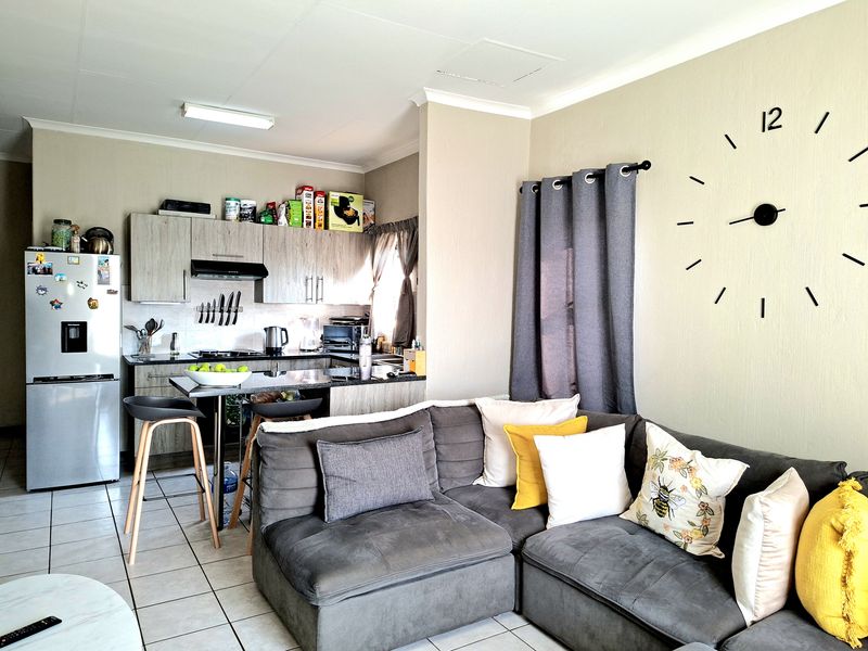 Open-plan living area featuring a modern kitchen with granite countertops and tiled flooring, seamlessly integrated with the lounge space.