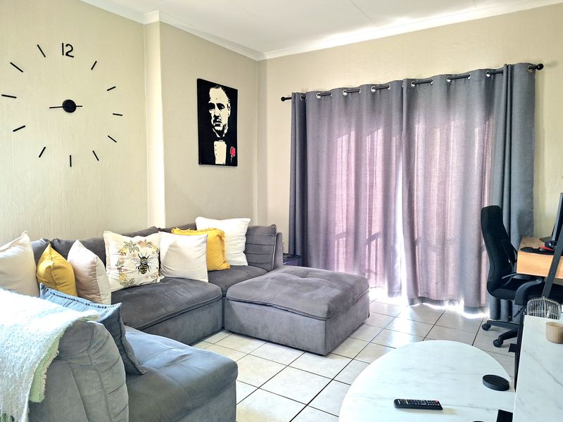 A comfortable living room featuring tiled flooring and a sliding glass door that provides access to the outdoor area.