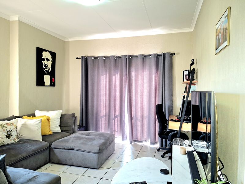 A living room featuring tiled flooring, coved ceilings, and a sliding glass door providing natural light.