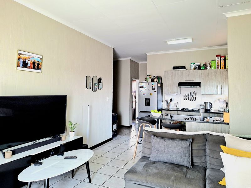 Open-plan living area featuring a modern kitchen with granite countertops, built-in cabinetry, and tiled flooring throughout the combined space.