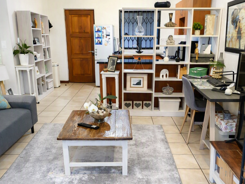 Open plan living area featuring tiled flooring, a timber entrance door, and a functional kitchen space with built-in cabinetry and countertops.