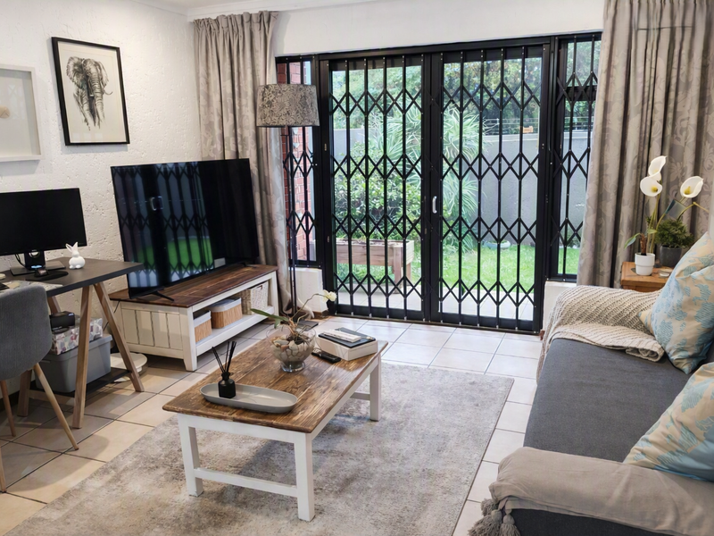 A bright living room featuring tiled flooring and a secure sliding glass door providing access to the outdoor area.