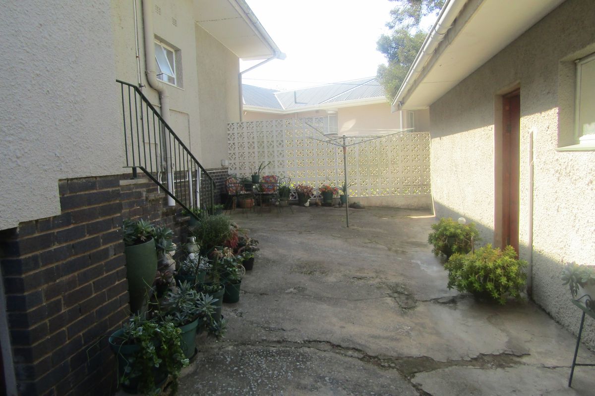 A rear courtyard area featuring concrete paving, a breeze block privacy wall, and an external metal staircase leading to the upper level.