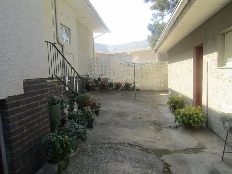 A rear courtyard area featuring concrete paving, a breeze block privacy wall, and an external metal staircase leading to the upper level.