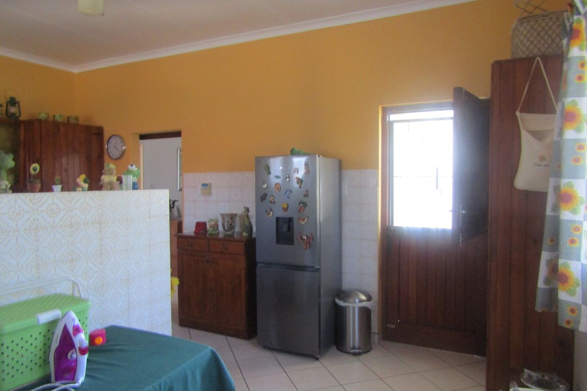 A functional kitchen area featuring tiled flooring, tiled splashbacks, and timber cabinetry with direct access to the exterior via a stable-style door.