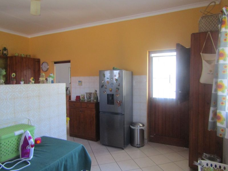 A functional kitchen area featuring tiled flooring, tiled splashbacks, and timber cabinetry with direct access to the exterior via a stable-style door.
