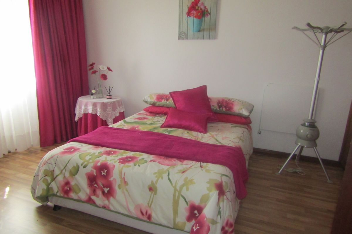 A bedroom featuring laminate flooring and a wall-mounted heater, providing a functional and comfortable sleeping space.