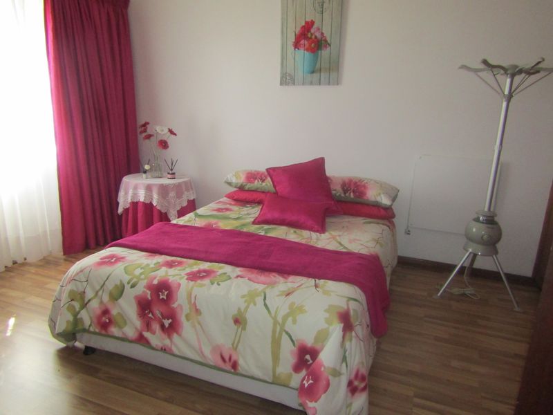 A bedroom featuring laminate flooring and a wall-mounted heater, providing a functional and comfortable sleeping space.