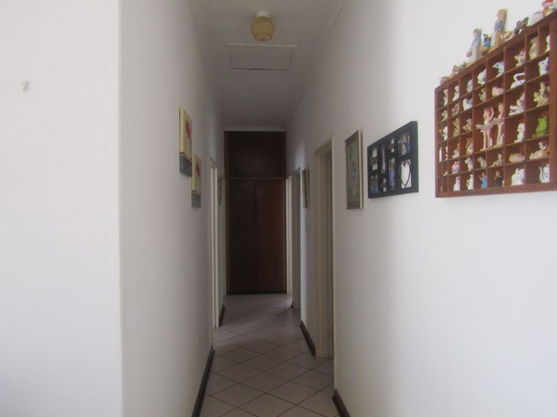 A functional hallway featuring tiled flooring, a built-in storage cupboard at the end, and a ceiling access hatch.