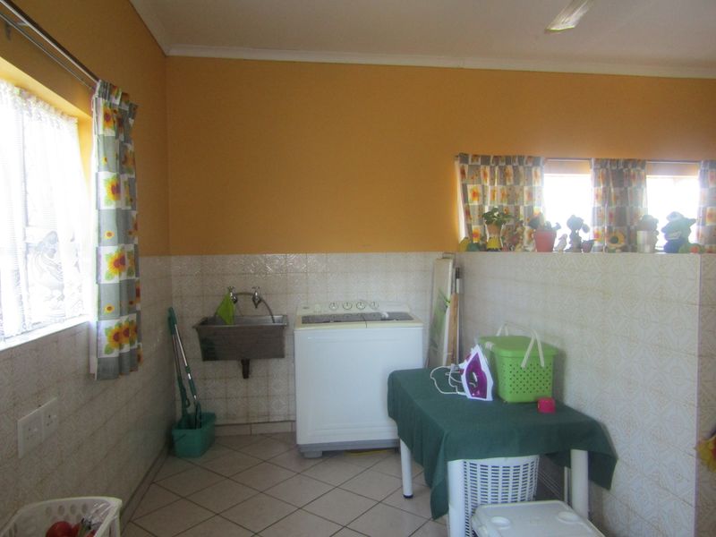 A functional laundry area featuring tiled walls and flooring, equipped with a wall-mounted utility sink and space for laundry appliances.