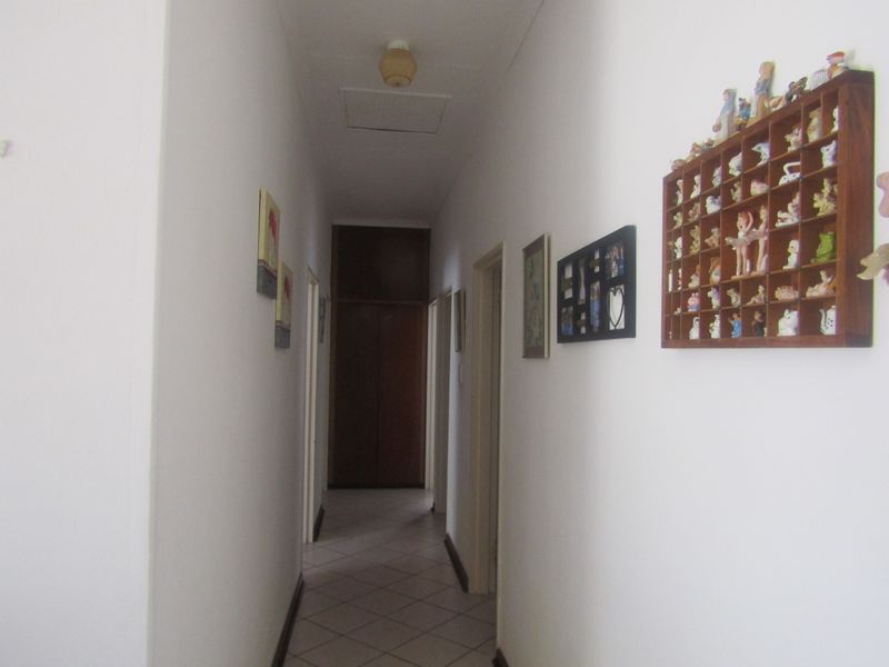 A functional hallway featuring tiled flooring and a built-in cupboard, providing access to various rooms within the home.