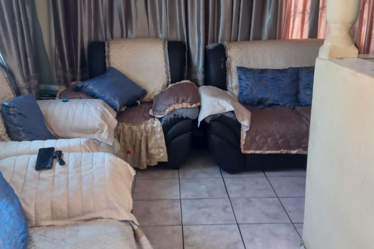 A living room area featuring tiled flooring and a partial room divider, providing a functional space for relaxation.