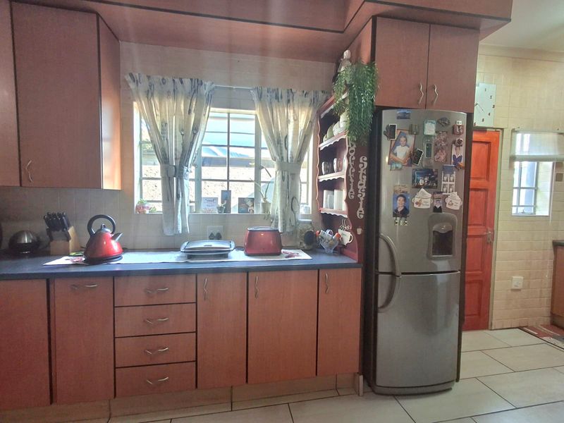A functional kitchen featuring laminate cabinetry, tiled flooring, and a window with security bars, offering a dated aesthetic ready for modernization.
