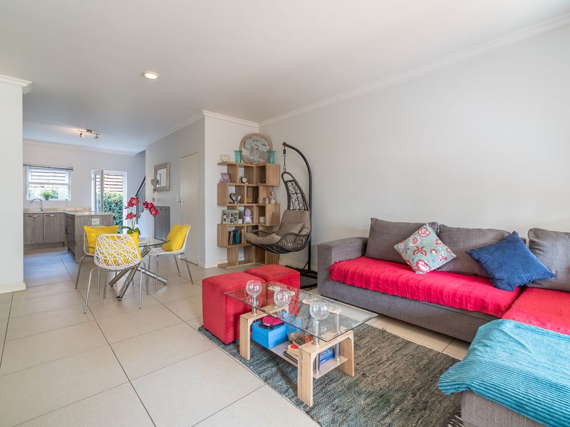 An open-plan living and dining area featuring neutral tiled flooring, recessed lighting, and a functional kitchen with modern cabinetry and an island.