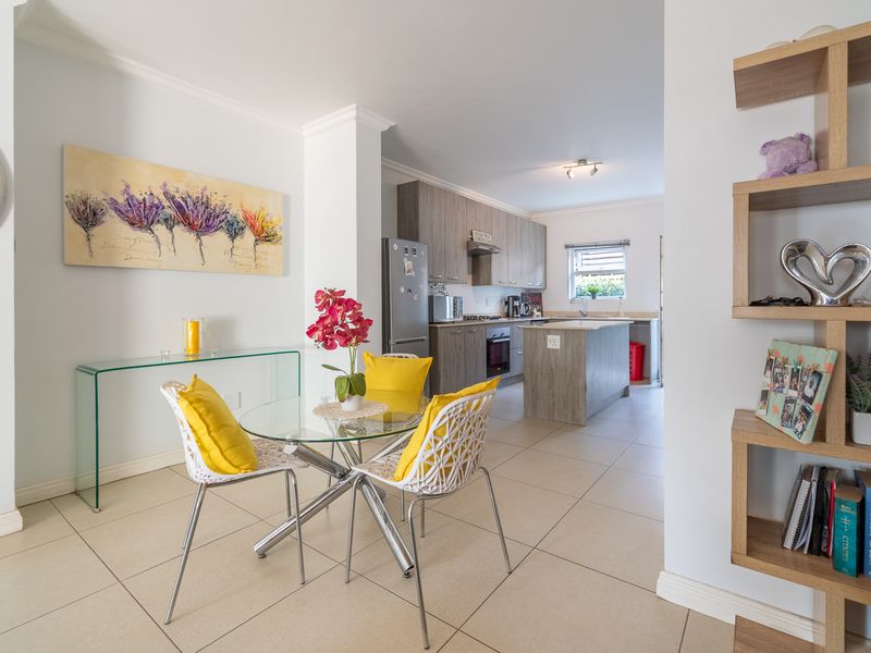 Open-plan living and kitchen area featuring modern cabinetry, a central kitchen island, built-in appliances, and neutral ceramic tile flooring throughout.