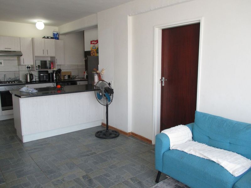 Open-plan living area featuring a functional kitchen with granite countertops, built-in oven, extractor fan, and durable tiled flooring throughout.