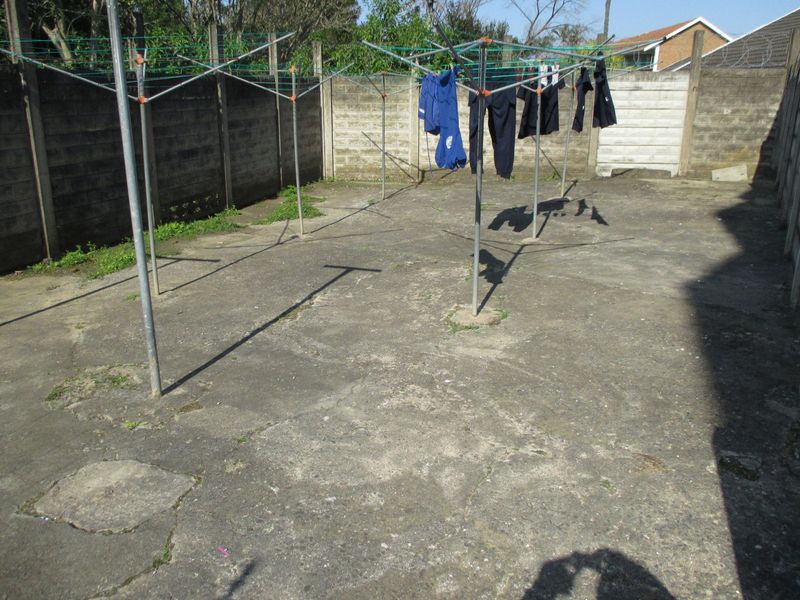 A paved rear courtyard area enclosed by precast concrete boundary walls, featuring multiple rotary washing lines.